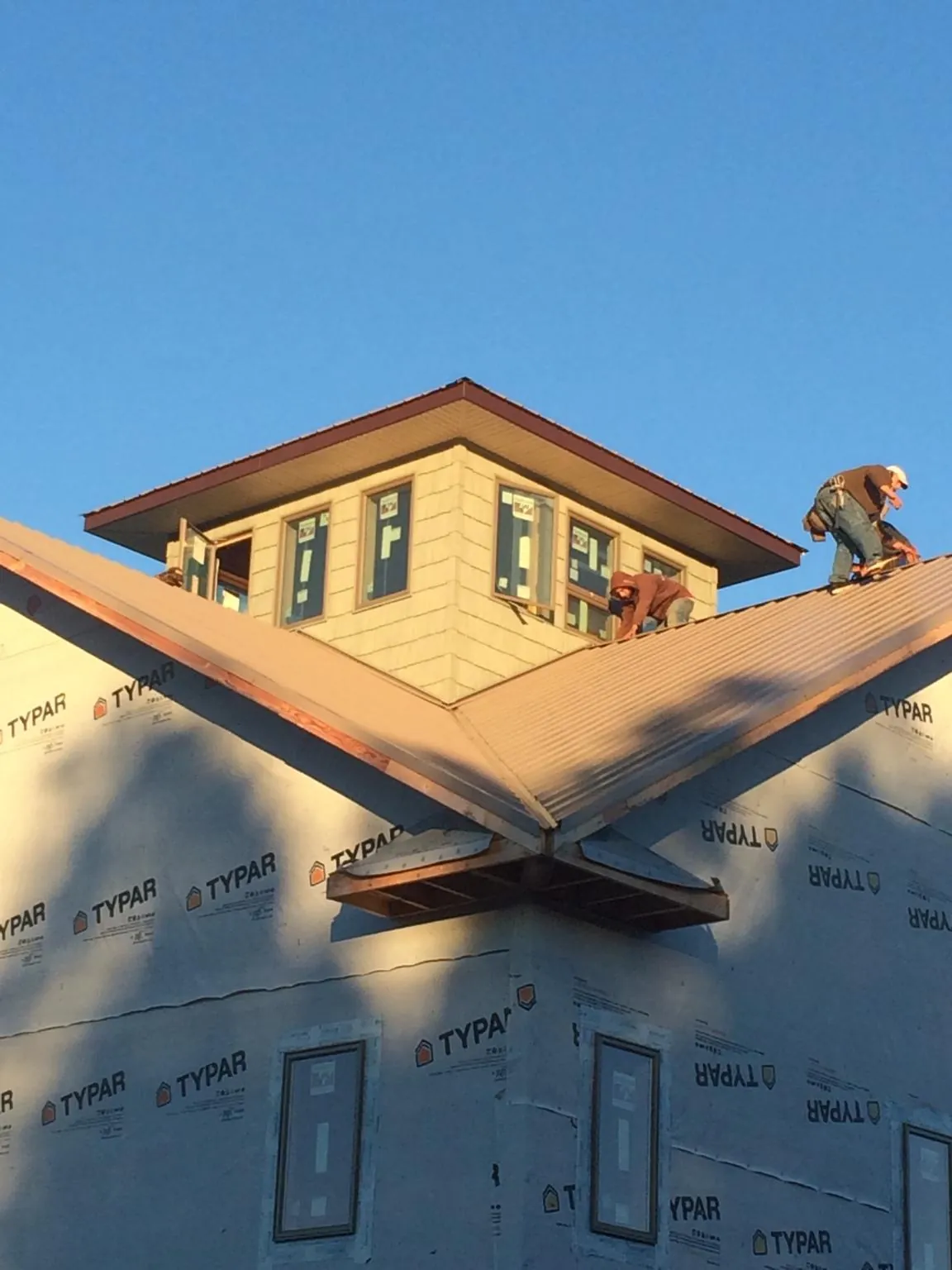 Roofers working around a rooftop cupola on a new metal roof at sunset — Roof Waterproofing in Riverton by Roofing Brothers